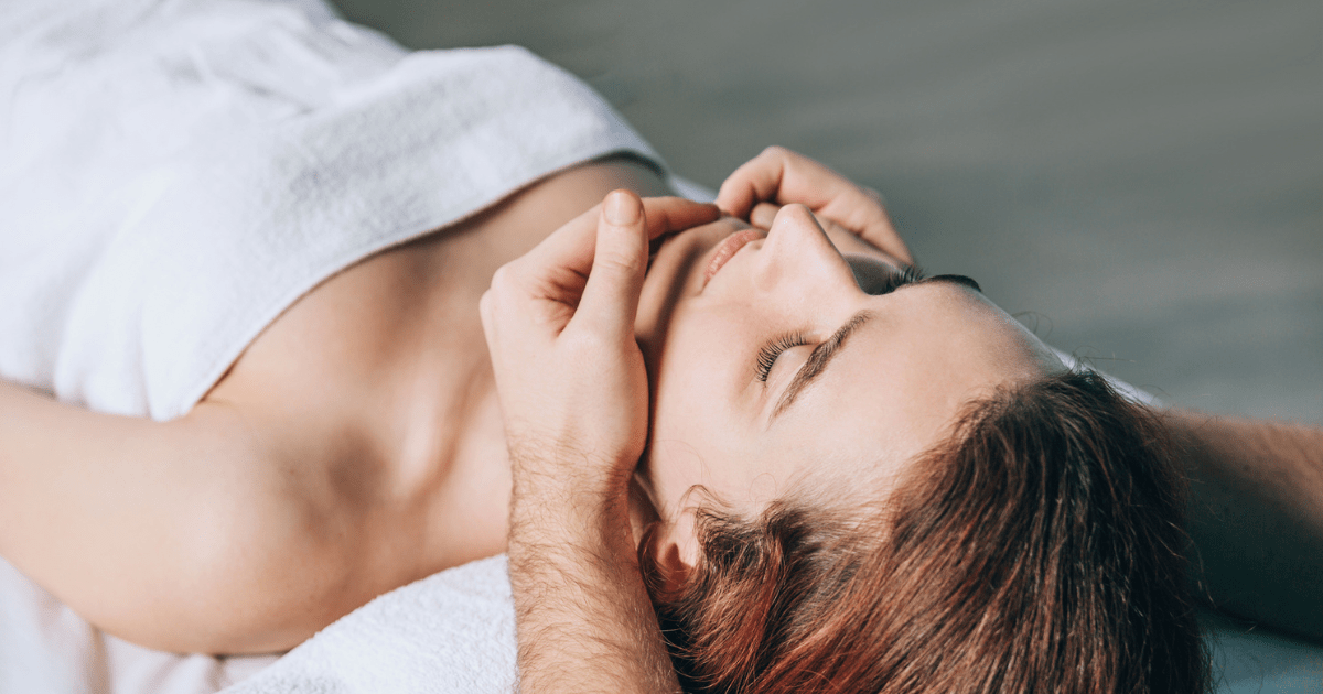 A woman receiving a relaxing facial massage at a spa.