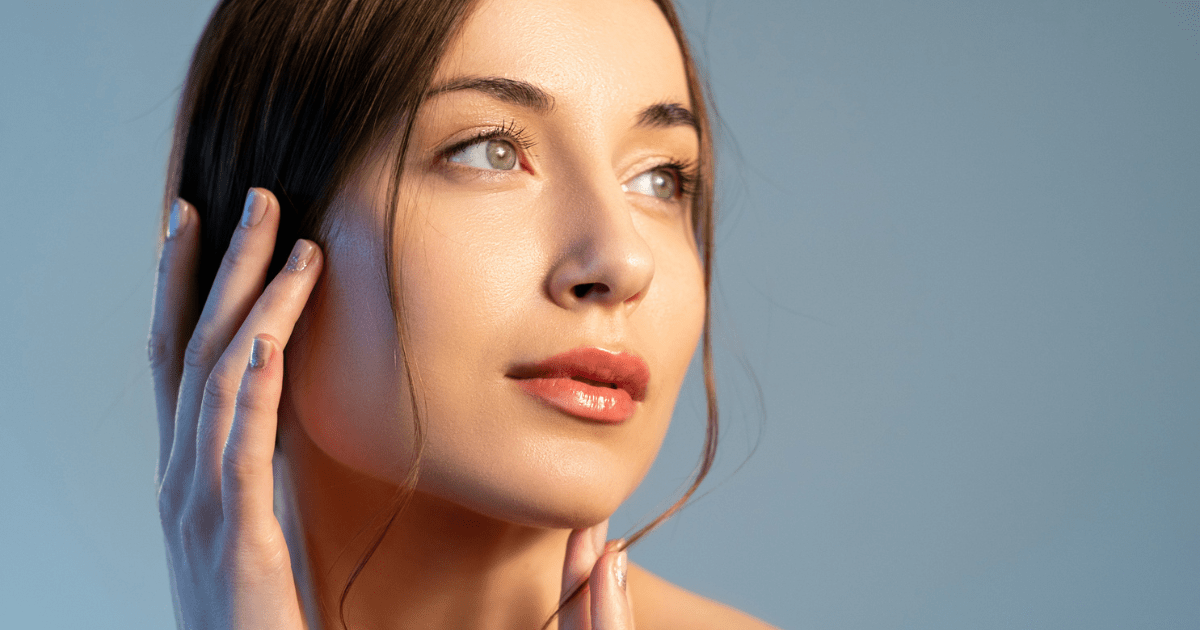 Woman looking into the distance with hands on her face.